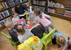 Grupa dzieci siedzi przy stoliku i ogląda książki