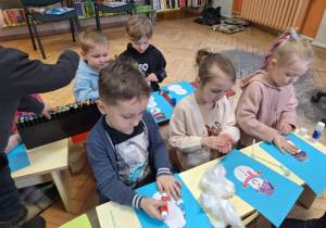 Grupa dzieci wykonuje prace plastyczną -bałwanka