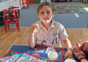 Julek siedzi przy stole i spożywa ciasto