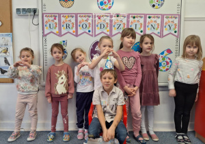 Julek siedzi na krześle i pozuje do zdjęcia z dziewczynkami