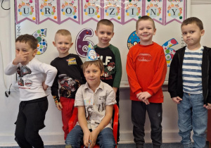 Julek siedzi na krześle i pozuje do zdjęcia z chłopcami