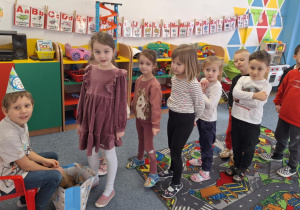 Julek siedzi na krześle a grupa dzieci składa mu życzenia