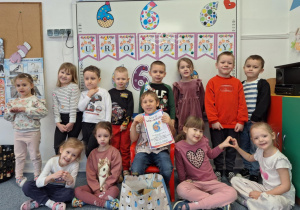 Julek siedzi na krześle i pozuje do zdjęcia z całą grupą