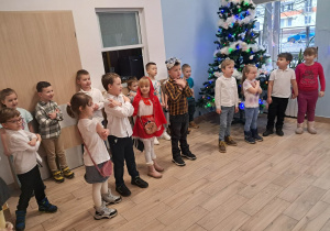 Grupa dzieci stojąca obok choinki