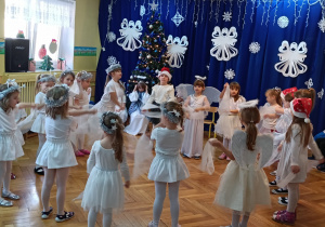 Dziewczynki w białych strojach tańczą z chustkami