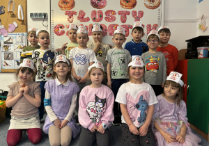 Grupa dzieci stoi przed napisem Tłusty czwartek