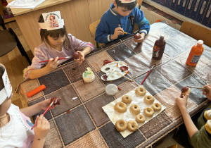 Dzieci przy stoliku malują kule brązową farbą