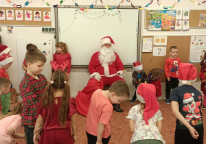 Grupa dzieci tańczy przed Mikołajem