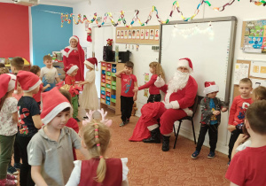 Grupa dzieci tańczy przed Mikołajem