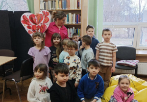 PANI BIBLIOTEKARKA Z WALENTYNKĄ, PRZED NIĄ STOI GRUPA DZIECI
