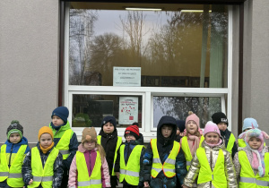 Grupa dzieci stoi przed budynkiem z napisem BIBLIOTEKA