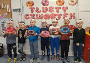 Grupa chłopców stoi na dywanie i pozuje do zdjęcia z obrazkami pączków