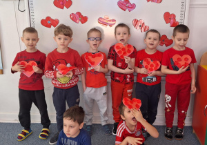 Chłopcy stoją i pozują do zdjęcia z sercami zrobinymi przez siebie