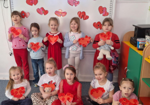 Dziewczynki stoją i pozują do zdjęcia z sercami zrobinymi przez siebie