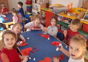 Grupa dzieci wykonuje pracę plastyczną przy stoliku