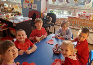 Grupa dzieci wykonuje pracę plastyczną przy stoliku