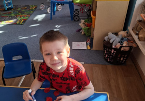 Chłopiec wykonuje pracę plastyczną przy stoliku