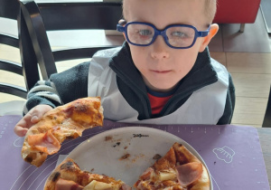 Chłopiec je pizzę przez siebie zrobioną