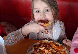 Dziewczynka je pizzę przez siebie zrobioną