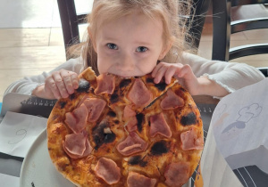 Dziewczynka je pizzę przez siebie zrobioną