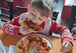 Chłopiec je pizzę przez siebie zrobioną
