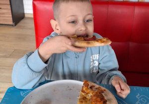 Chłopiec je pizzę przez siebie zrobioną
