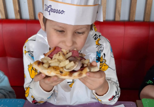 Chłopiec je pizzę przez siebie zrobioną