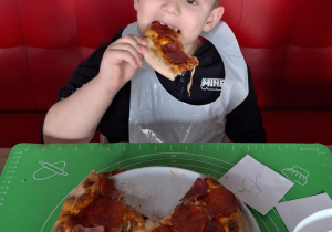 Chłopiec je pizzę przez siebie zrobioną