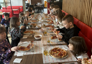 Dzieci spożywają pizzę