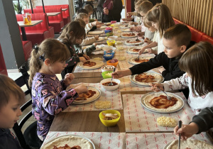 Dzieci smarują pizzę pulpą pomidorową