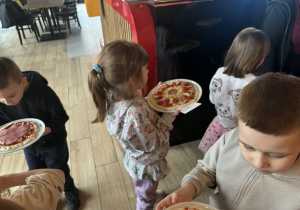 Dzieci niosą pizzę do upieczenia
