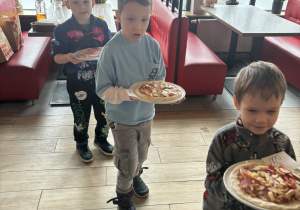 Dzieci niosą pizzę do upieczenia