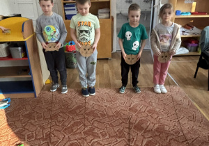 Dzieci nawijają sznurek z myszką na głowę kota