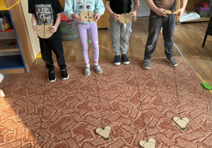 Dzieci nawijają sznurek z myszką na głowę kota