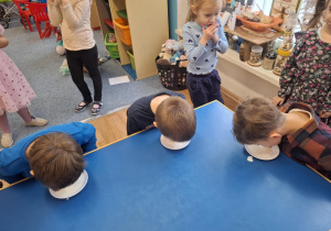 Grupa dzieci siedzi przy stoliku i pije mleko z talerzyka językiem jak kot