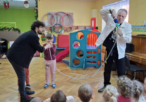 Dzieci obserwują grę na instrumencie stworzonym przez prowadzących