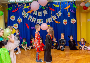 Dzieci tańczą w parach trzymając balon czołami