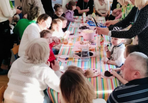 Dzieci i dziadkowie siedzą przy wspólnym poczęstunku