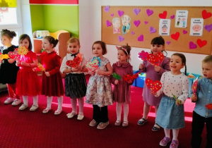 Dzieci mówią wiersz dla babci i dziadka trzymając w rękach rekwizyty