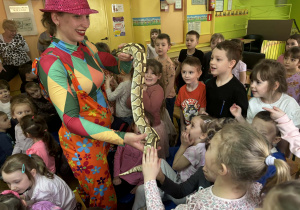 Pani w kolorowym stroju pokazuje dzieciom węża