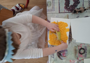 Dziewczynka wykonuje w glinie odcisk dinozaura