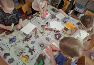 Dzieci wykonują w glinie odciski dinozaurów
