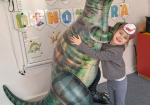 Dziewczynka pozuje do zdjęcia z dmuchanym dinozaurem