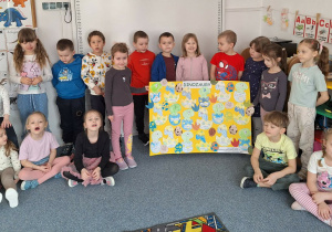 Dzieci pozują do zdjęcia z plakatem zrobionych przez siebie odrazków małych dinozaurów