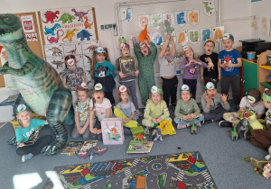 Grupa dzieci pozuje do zdjęcia z dmuchanym dinozaurem