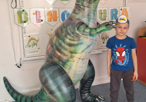 Chłopiec pozuje do zdjęcia z dmuchanym dinozaurem