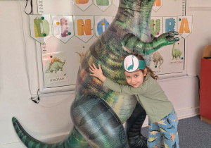 Dziewczynka pozuje do zdjęcia z dmuchanym dinozaurem