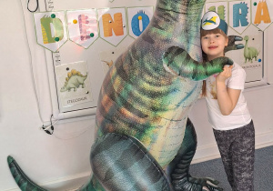 Dziewczynka pozuje do zdjęcia z dmuchanym dinozaurem