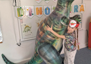 Dziewczynka pozuje do zdjęcia z dmuchanym dinozaurem