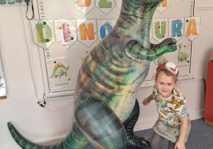 : Dziewczynka pozuje do zdjęcia z dmuchanym dinozaurem
